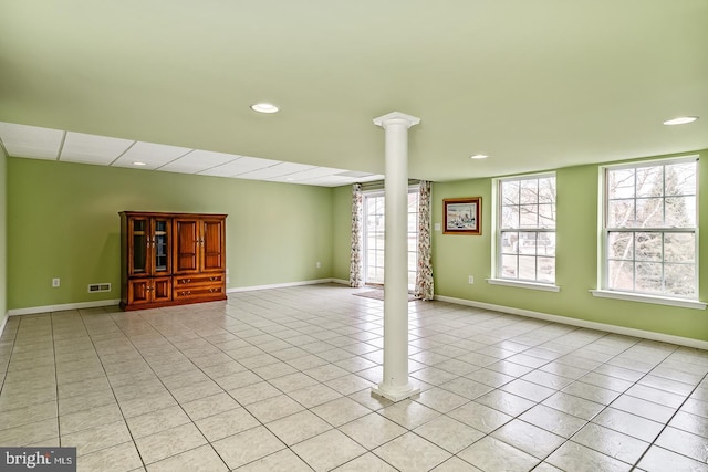 spare room featuring a wealth of natural light, baseboards, light tile patterned flooring, and ornate columns