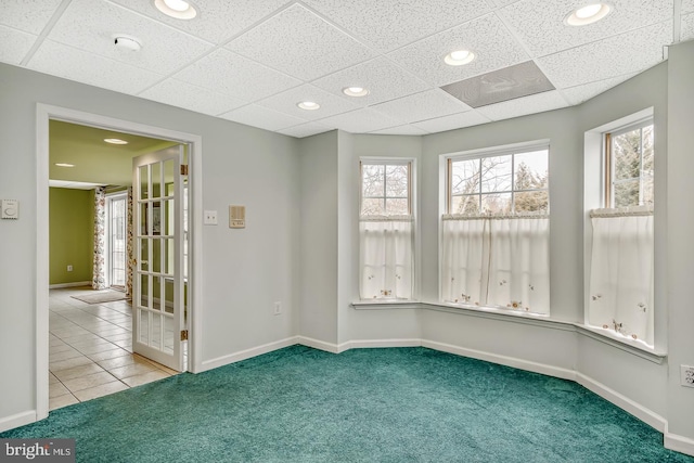 carpeted empty room featuring tile patterned flooring, baseboards, and a wealth of natural light