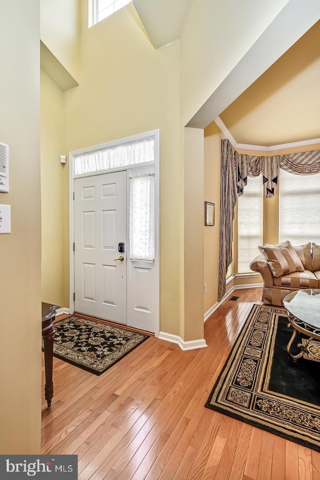 foyer with a high ceiling, hardwood / wood-style flooring, and baseboards