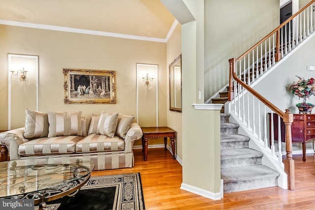 living room featuring stairs, baseboards, wood finished floors, and crown molding