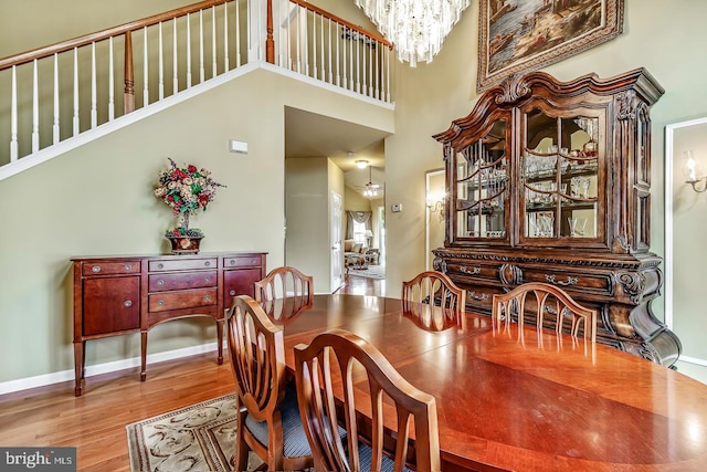 dining area with an inviting chandelier, a high ceiling, baseboards, and wood finished floors