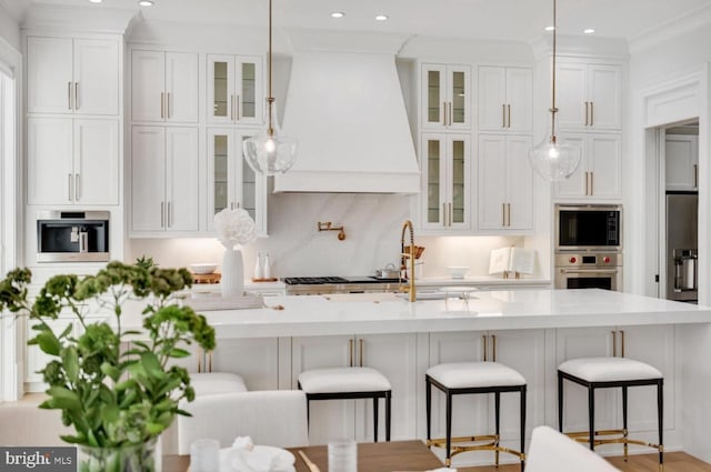 kitchen with appliances with stainless steel finishes, light countertops, white cabinets, and custom range hood