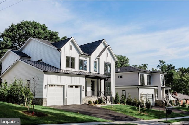 modern farmhouse with aphalt driveway, board and batten siding, a front yard, a standing seam roof, and metal roof