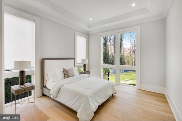 bedroom with a tray ceiling, recessed lighting, wood finished floors, and baseboards