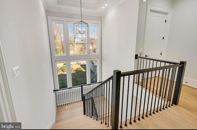 stairway with recessed lighting, wood finished floors, a towering ceiling, baseboards, and an inviting chandelier