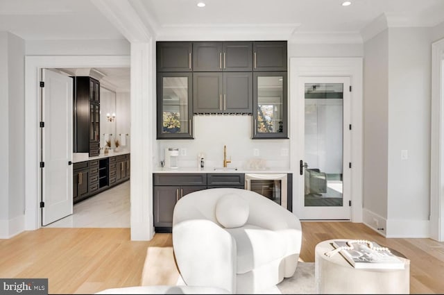 bar featuring beverage cooler, light wood-style flooring, indoor wet bar, a sink, and recessed lighting