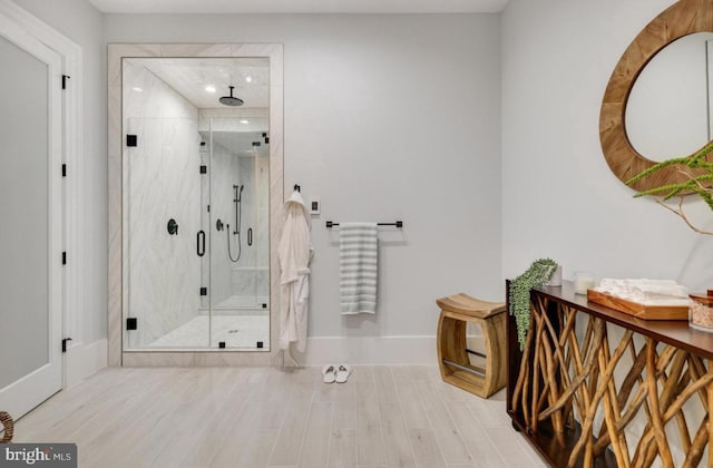 full bath with baseboards, a marble finish shower, and wood finished floors