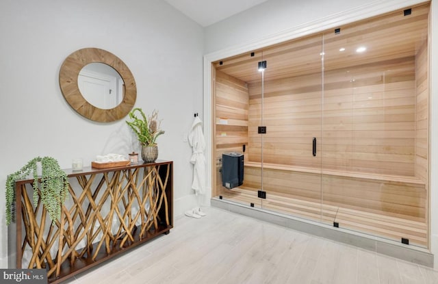 interior space with recessed lighting, a sauna, a shower stall, and wood finished floors