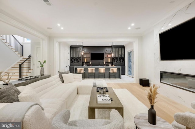 living area with recessed lighting, a premium fireplace, visible vents, ornamental molding, and stairway