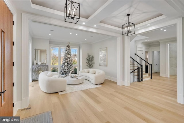 sitting room with stairs, a tray ceiling, light wood-style floors, and a notable chandelier