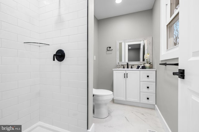 full bathroom featuring marble finish floor, a tile shower, vanity, and toilet