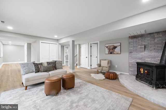 living area with a wood stove, visible vents, and wood finished floors