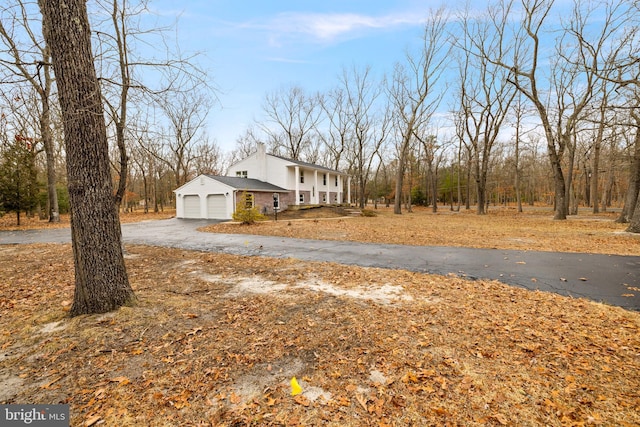 view of side of property featuring driveway, a chimney, and an attached garage