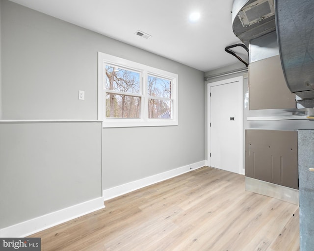 interior space featuring light wood-type flooring, visible vents, and baseboards