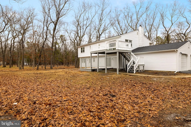 back of property with a deck, an outbuilding, a garage, stairway, and a chimney