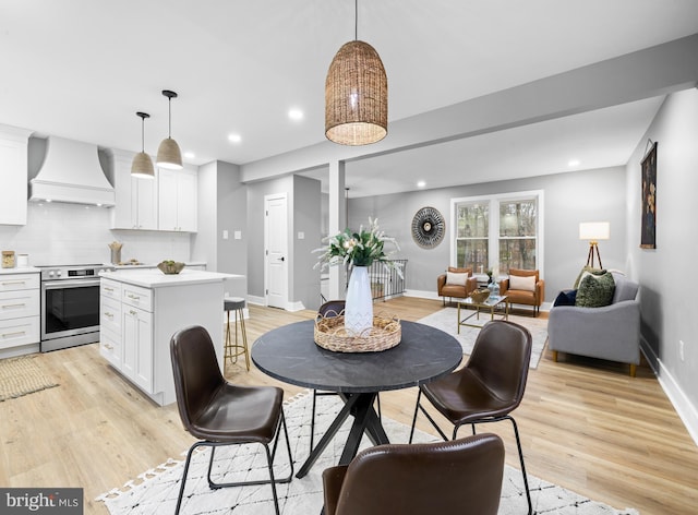 dining room with recessed lighting, light wood-style flooring, and baseboards