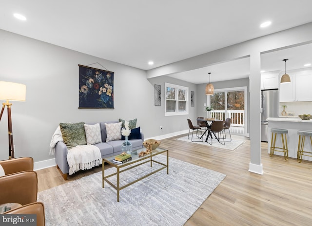 living area with baseboards, recessed lighting, and light wood-style floors