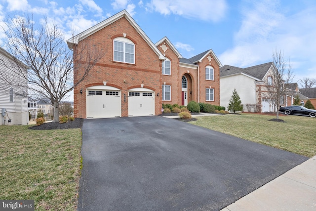 traditional-style home with a garage, driveway, a front yard, and brick siding