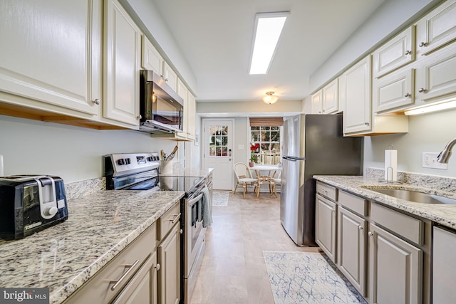 kitchen featuring light stone counters, a toaster, a sink, white cabinets, and appliances with stainless steel finishes