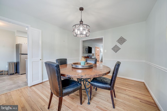 dining space with a notable chandelier, baseboards, and light wood-style floors