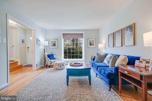 living room featuring visible vents, baseboards, wood finished floors, and stairs