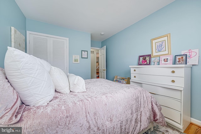 bedroom with wood finished floors, a closet, and baseboards