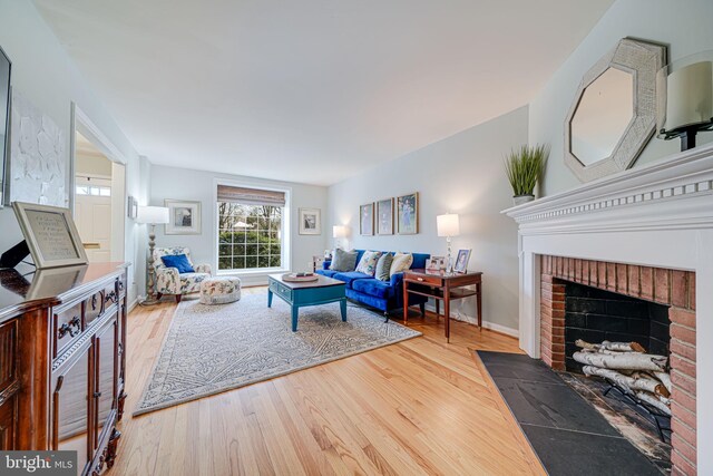 living area with a brick fireplace, baseboards, and wood finished floors