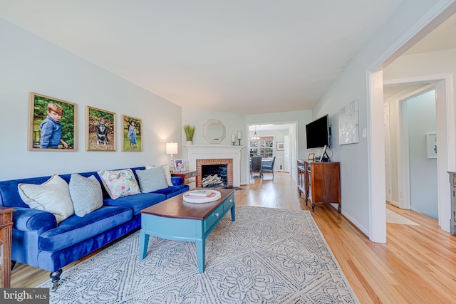 living room with baseboards, light wood-style floors, and a brick fireplace