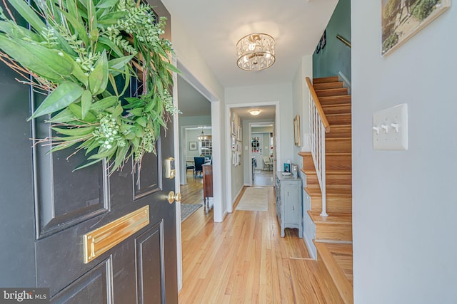 foyer featuring a chandelier, stairway, light wood-style flooring, and baseboards