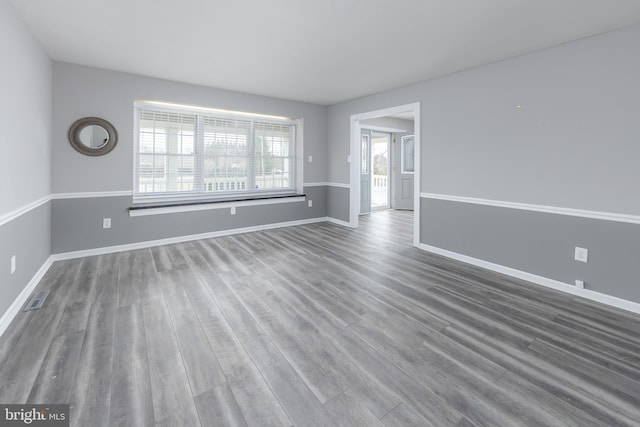 empty room featuring visible vents, baseboards, and wood finished floors