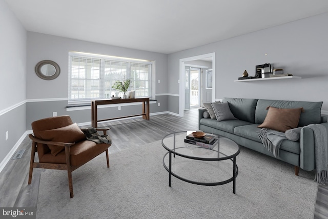 living area with visible vents, baseboards, and wood finished floors