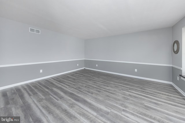 unfurnished room with wood finished floors, visible vents, and baseboards