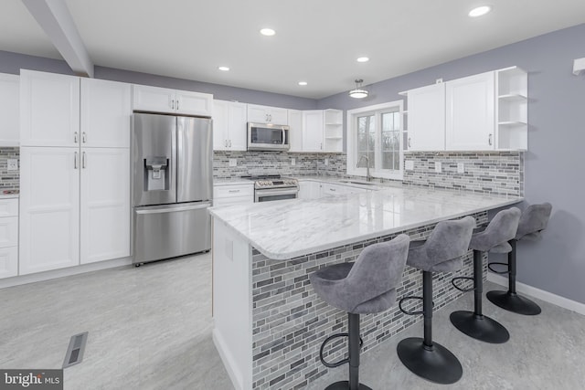 kitchen featuring white cabinetry, open shelves, appliances with stainless steel finishes, and a sink