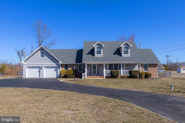 cape cod house featuring aphalt driveway, covered porch, a front yard, a shingled roof, and brick siding