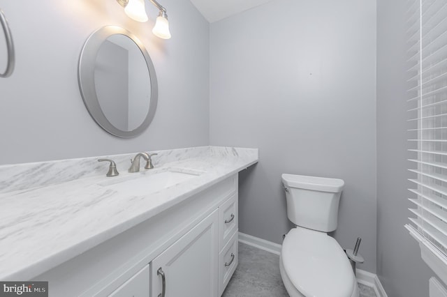 half bath featuring toilet, vanity, and baseboards