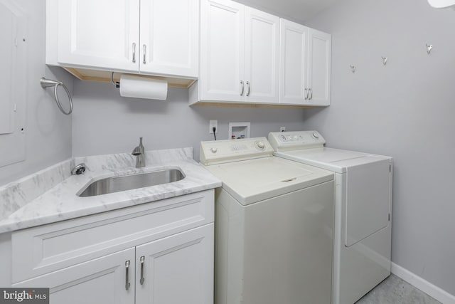 laundry room featuring a sink, baseboards, cabinet space, and independent washer and dryer