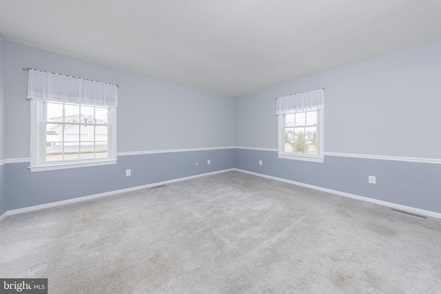 carpeted empty room featuring visible vents and baseboards