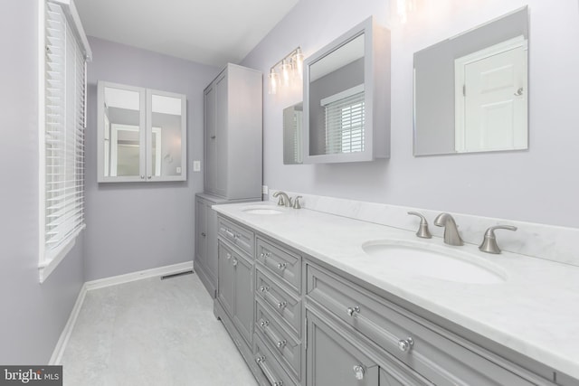 bathroom with double vanity, baseboards, and a sink