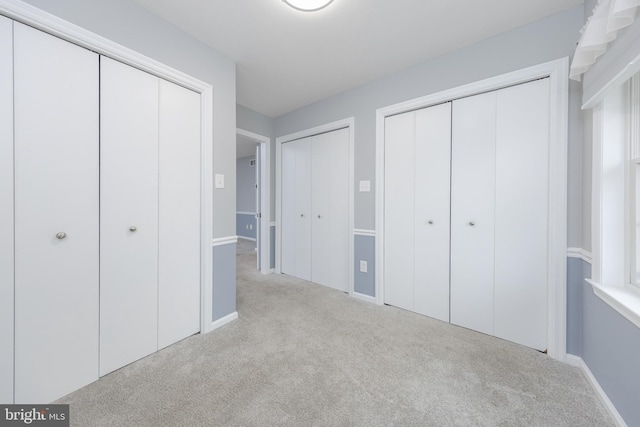 unfurnished bedroom featuring two closets and carpet floors