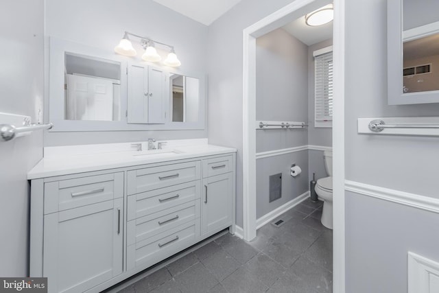 bathroom with visible vents, baseboards, toilet, and vanity