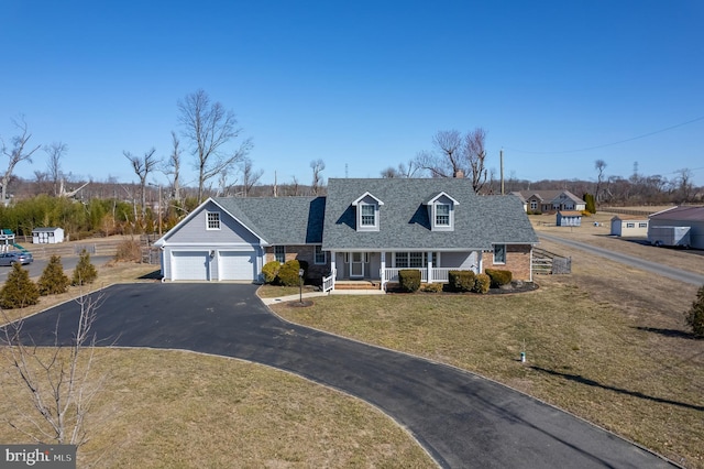 cape cod home with a shingled roof, a front lawn, aphalt driveway, covered porch, and an attached garage