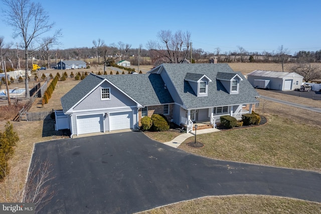 view of front of property featuring a shingled roof, a residential view, a porch, a front yard, and driveway