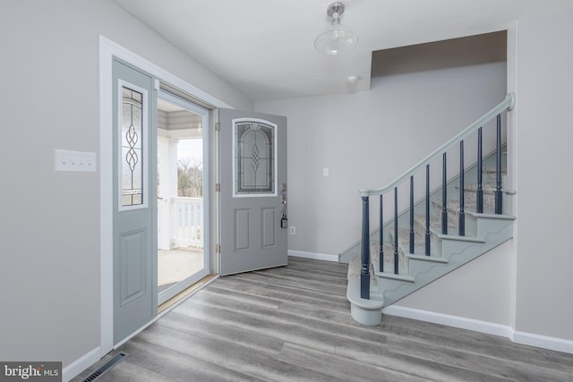 foyer featuring visible vents, stairway, wood finished floors, and baseboards