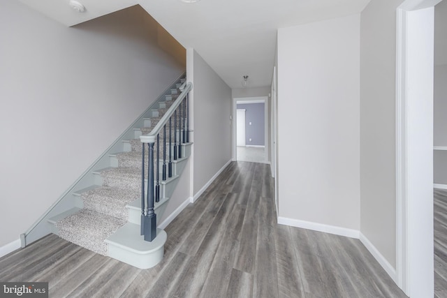 staircase featuring wood finished floors and baseboards