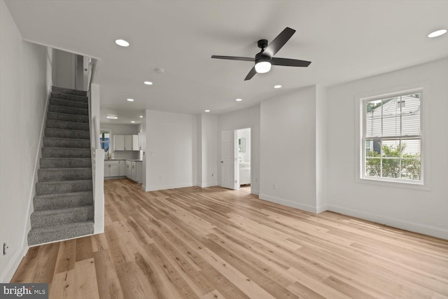 unfurnished living room featuring light wood finished floors, recessed lighting, a ceiling fan, baseboards, and stairs