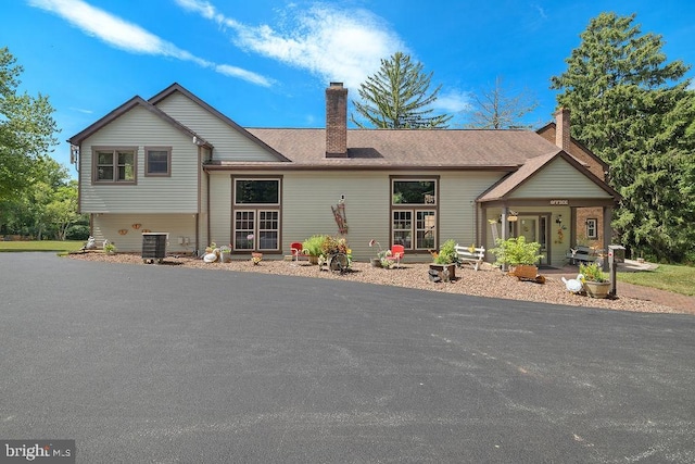 view of front of house with central AC unit and a chimney