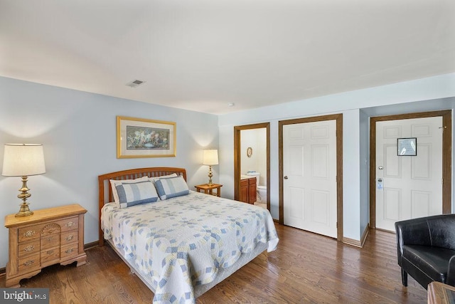 bedroom featuring dark wood-type flooring, visible vents, connected bathroom, and baseboards