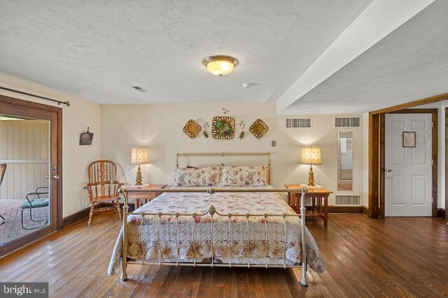 bedroom featuring a textured ceiling, visible vents, and wood finished floors