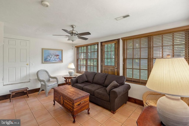 living area featuring baseboards, light tile patterned flooring, visible vents, and a ceiling fan