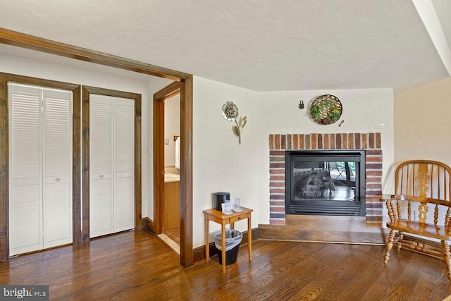 sitting room featuring a fireplace, a textured ceiling, baseboards, and wood finished floors